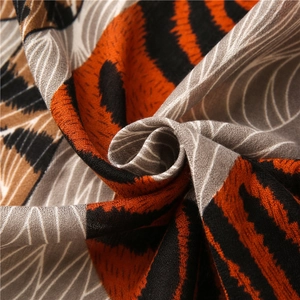 Détail de foulard tissé avec rayures de tigre orange et motifs de plumes grises