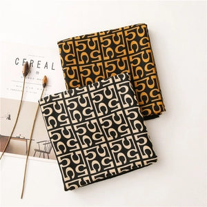 Classic cotton linen monogram scarf with yellow and beige knit patterns in a flat lay