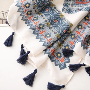 Détail d'une écharpe en lin doux avec motifs géométriques et pompons bleu foncé