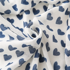 Detailed texture of white cotton linen scarf featuring blue heart pattern print