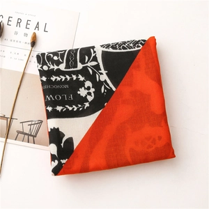 Close-up of lightweight scarf with bold orange and black-white letter print pattern