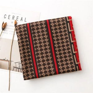 Close-up of geometric monogram pattern scarf with red stripes and textured fabric