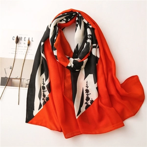 Flat lay of a red and black graffiti print scarf with dried flower and magazine decor