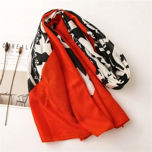 Detail of floral print scarf with orange and black blocks next to a magazine