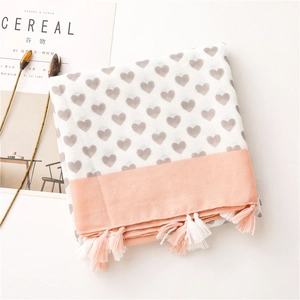 Flat lay of cream linen scarf with grey hearts, pink borders, and tasseled edges