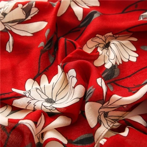 Close-up of lightweight floral fabric with red background and white lily patterns