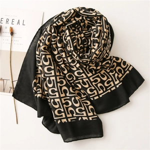Detail of elegant black and beige cotton linen scarf with geometric letter pattern