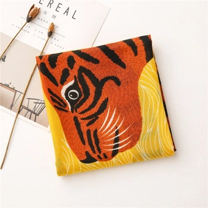 Détail d'une écharpe à imprimé tigre avec un magazine Cereal et des fleurs séchées