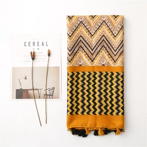 Detail view of woven wave pattern scarf with yellow, brown tassels and magazine prop