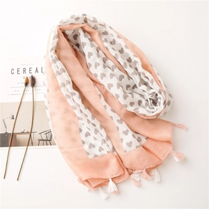 Macro detail of soft cotton linen scarf with heart patterns and pink tassel trim