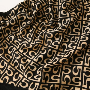 Macro shot of cotton linen scarf texture featuring black and gold geometric letter patterns