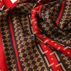 Detailed macro view of retro monogram print scarf with red and black geometric patterns