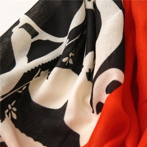 Detail view of double-sided scarf with black-white abstract print and vibrant orange fabric