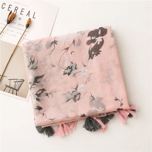 Close-up of pink floral scarf with elegant leaf patterns and stylish fringe tassels