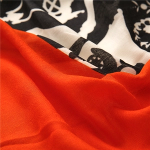 Detail of soft chiffon scarf showing vibrant orange and artistic black graffiti pattern