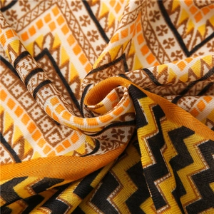 Detailed close-up of vibrant yellow and orange geometric zigzag patterns on a soft scarf