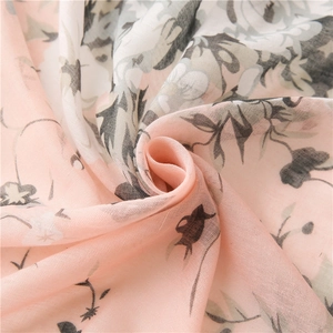 Macro view of light pink floral silk scarf showing soft fabric texture and drape