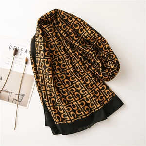 Detail view of cotton linen scarf featuring black and gold geometric monogram patterns
