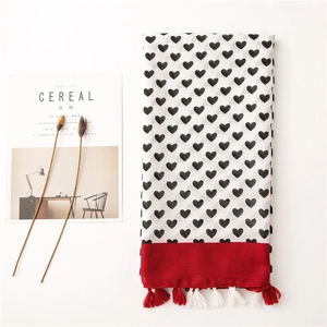 Detailed flat lay of a cotton-linen scarf with heart print, red border, and fringe tassels