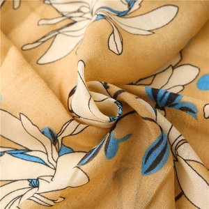 Macro detail of mustard yellow floral scarf fabric showing soft weave and texture