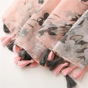 Close-up of lightweight floral shawl with dual-color tassel fringe and soft pink flower print