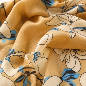 Detailed macro view of soft ginger yellow floral print fabric with ivory blossom patterns