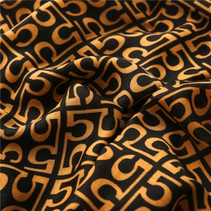 Macro view of cotton linen scarf with orange letter patterns and smooth fabric texture