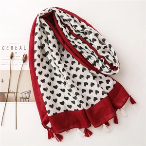 Flat lay of heart print cotton linen scarf with red tassels next to dried flowers