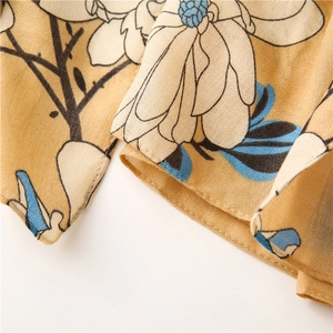 Close-up of ginger yellow cotton scarf with delicate cream floral patterns and fine texture