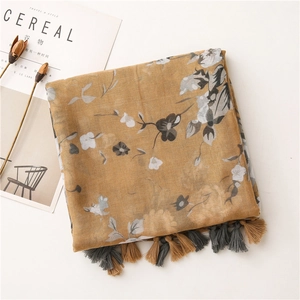 Close-up of yellow floral scarf with tassel details and artistic minimalist background