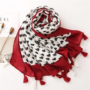 Detail of red and white heart print scarf with decorative tassels and soft cotton texture