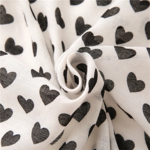 Detailed macro view of soft cotton-linen fabric with black heart patterns and elegant drapes