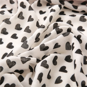 Macro shot of white cotton linen fabric with black heart patterns and soft texture