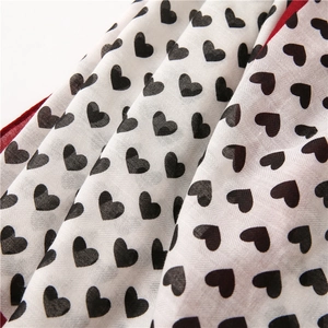 Close-up of cotton linen scarf featuring black heart patterns and red hem detail