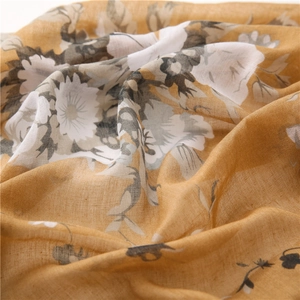 Macro detail of breathable mustard yellow floral scarf with soft pleated fabric texture