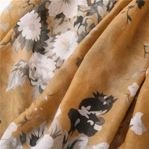 Detail of floral chiffon fabric with ginger yellow base and elegant white flower patterns