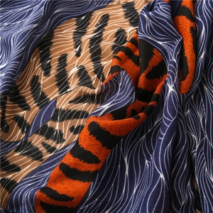 Détail d'une écharpe légère avec imprimé léopard orange et motifs de lignes bleues