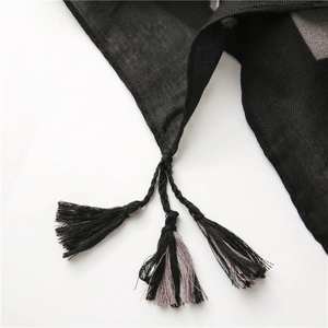 Dettaglio di sciarpa a spina di pesce con nappe intrecciate a mano in nero e grigio