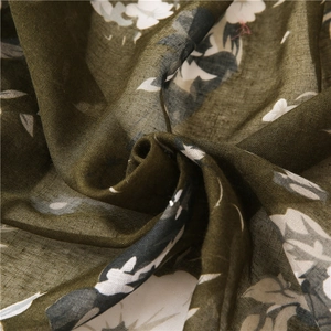 Macro shot of dark green floral shawl fabric showing fine texture and soft drape