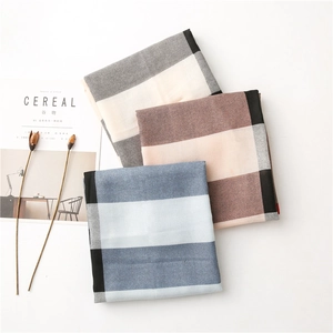 Détail de texture de foulards à carreaux empilés en gris, marron moka et bleu ciel