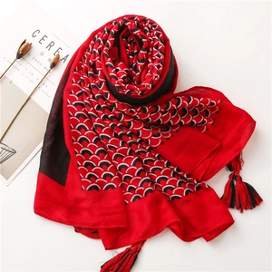 Dettaglio di sciarpa in cotone e lino con motivo a squame rosse e nappe sfrangiate