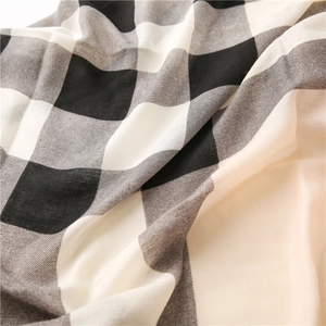 Gros plan sur le tissage à carreaux noir et blanc et le drapé doux du tissu de l'écharpe