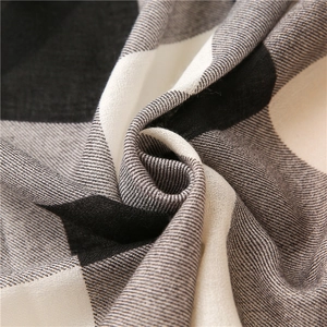Texture macro d'une écharpe à carreaux montrant un tissu tissé en noir, gris et beige