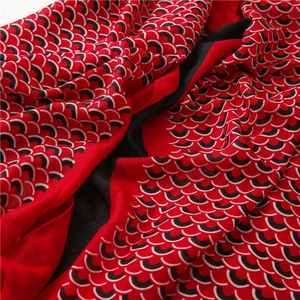 Dettaglio macro della sciarpa in cotone lino con motivo a squame rosse e nere e trama fine