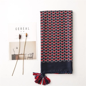 Dettaglio di sciarpa blu navy con motivi colorati a squame di pesce e nappe sfrangiate