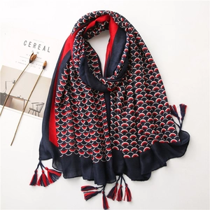 Dettaglio di sciarpa con motivo a scaglie di pesce blu e rosso e finitura con nappe chic