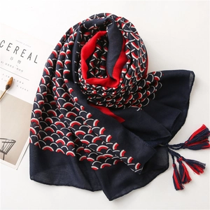 Dettaglio dello scialle in cotone e lino blu navy con motivi a onde rosse e nappe