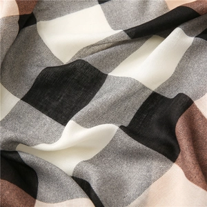 Gros plan sur le tissu d'une écharpe à carreaux marron et noir montrant la texture douce
