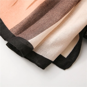 Détail d'une écharpe douce montrant le tissage fin et le motif à blocs de couleurs chaudes