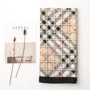 Detailed close-up of a classic plaid cotton scarf with black edges and chic fringe